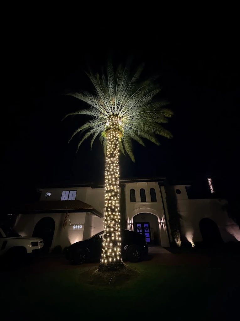 Two-story home with warm white lights and wreaths