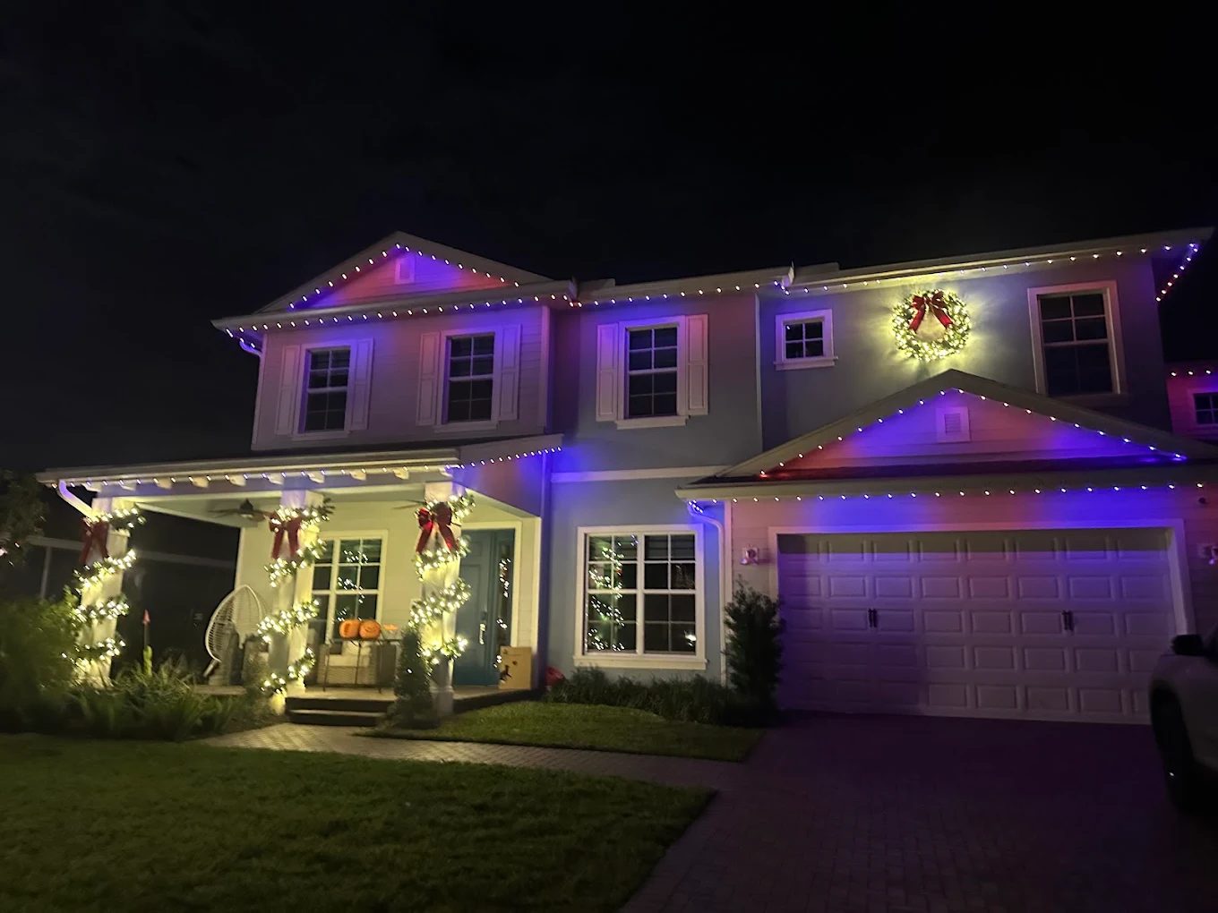 Two-story home with warm white holiday lighting