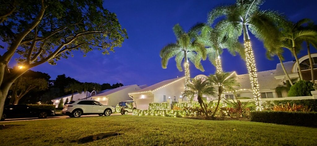 HOA community entrance with wrapped palms and lit sign in Jupiter