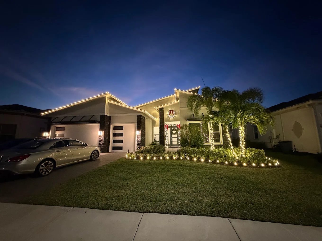 Pool area with palms wrapped in holiday lights